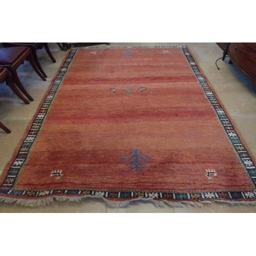 571 - A red ground woolen rug with geometric boarders - the field covered in animal motifs - 2.8m x 2.07m