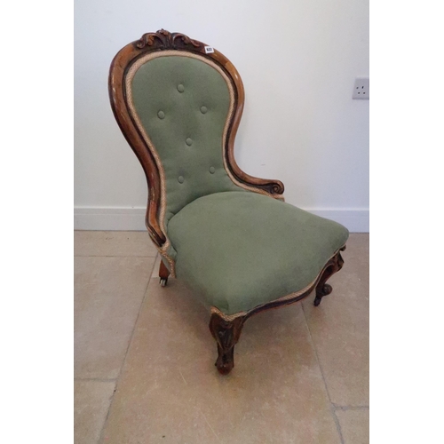 622 - An early 20th century nursing chair upholstered in green fabric terminating in casters