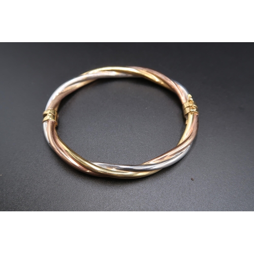 145 - A 9ct tri colour gold twist hinged bangle. Weight 9.47 grams