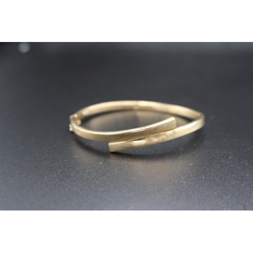 146 - A 9ct gold crossover style bangle. Weight 7.03 grams.