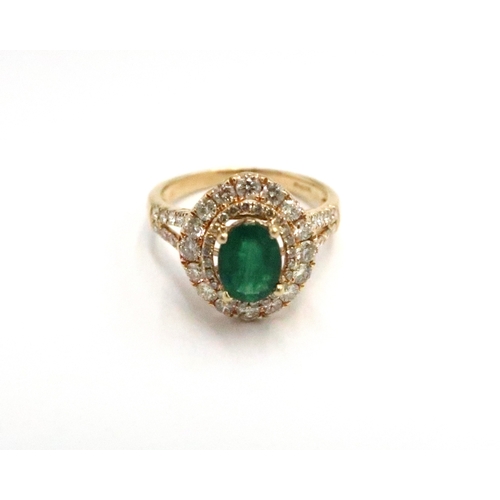 An 18ct yellow gold dress ring with oval cut emerald 1.5ct, surrounded by a double halo of diamonds 1.1ct - approx weight 5.7grams - ring Size P