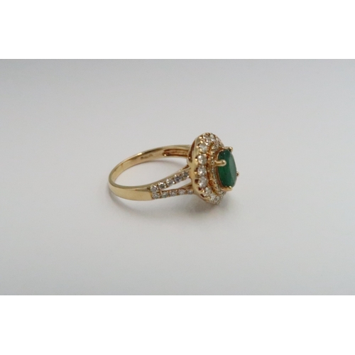  An 18ct yellow gold dress ring with oval cut emerald 1.5ct, surrounded by a double halo of diamonds ... 