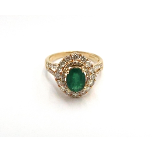  An 18ct yellow gold dress ring with oval cut emerald 1.5ct, surrounded by a double halo of diamonds ... 