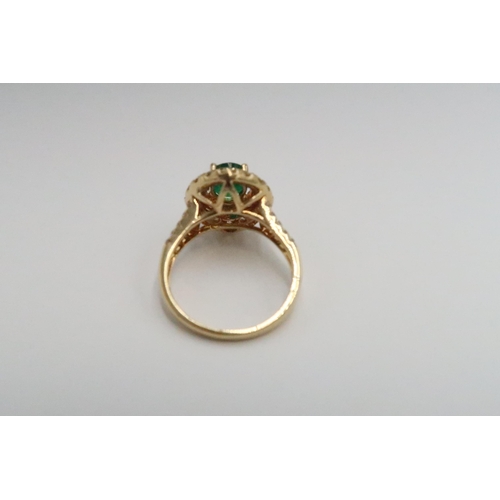  An 18ct yellow gold dress ring with oval cut emerald 1.5ct, surrounded by a double halo of diamonds ... 