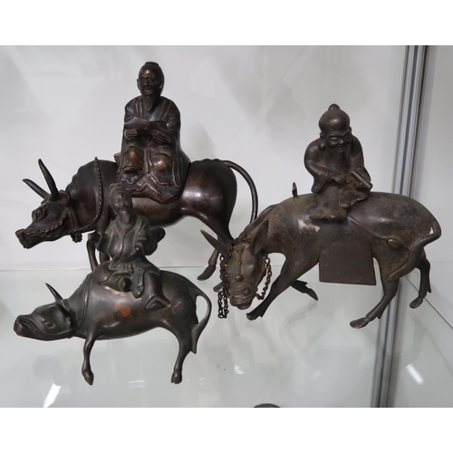  A group of three Chinese bronze incense burners in the form of water buffalo, each being ridden by a... 