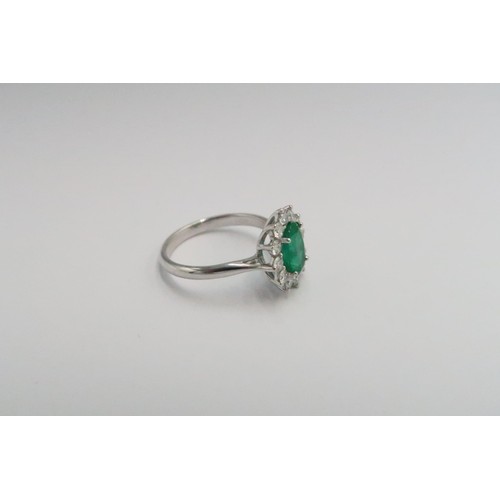  A platinum emerald and diamond dress ring - The central oval cut emerald surrounded by 12 diamonds -... 