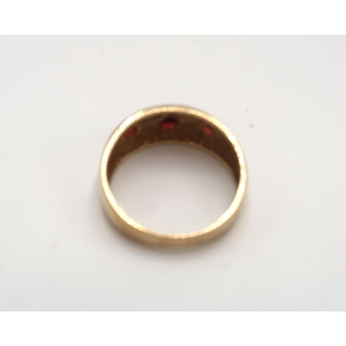 91 - A 9ct gold band ring gypsy set with three garnets. Size S. Weight 4.30 grams