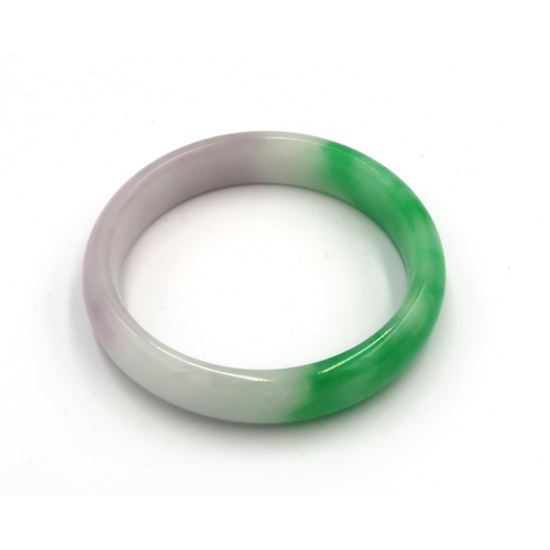 23 - A green and white jade bangle 72mm diameter. 14mm wide. Weight 53.48 grams