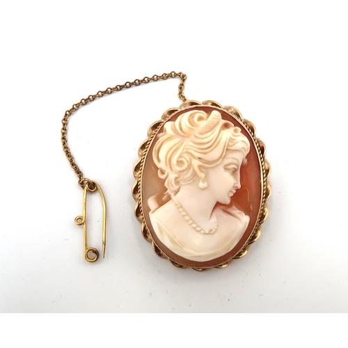 65 - A cameo brooch in 9ct gold mount with rope twist border and pie-crust edge, hallmarked to the pendan... 