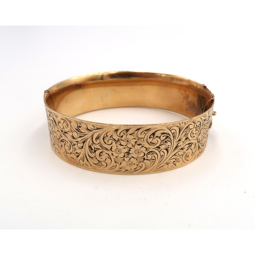 66 - A 9ct gold and solid metal core, Victorian style bangle, hinged with two panels, one foliate engrave... 