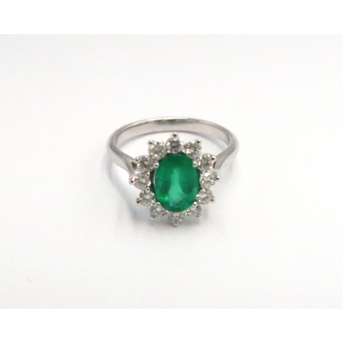 204 - A platinum emerald and diamond dress ring - The central oval cut emerald surrounded by 12 diamonds -... 