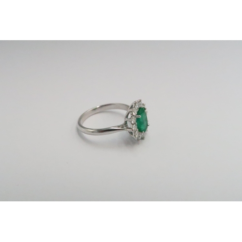 204 - A platinum emerald and diamond dress ring - The central oval cut emerald surrounded by 12 diamonds -... 