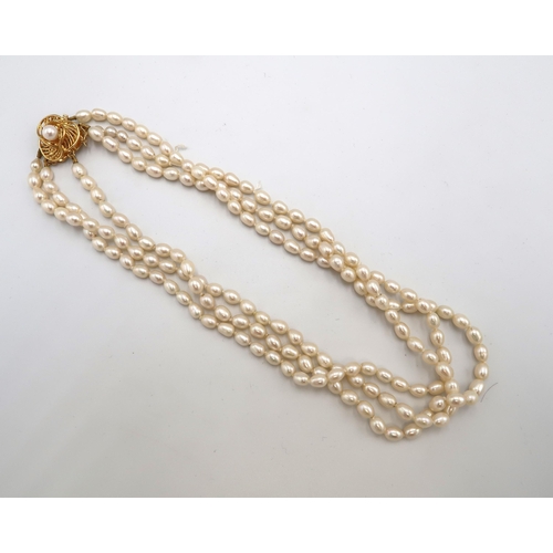 143 - An 18ct gold and freshwater pearl three strand necklace, the triform flowerhead clasp set with centr... 