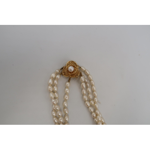 143 - An 18ct gold and freshwater pearl three strand necklace, the triform flowerhead clasp set with centr... 