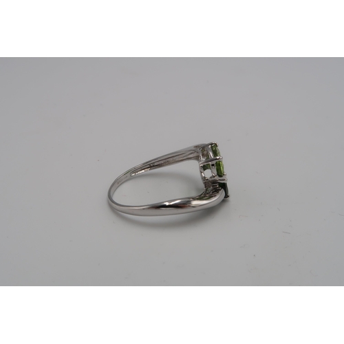 152 - A 9ct white gold and green stone crossover ring, likely peridot and tsavorite, size U, 3.9g.