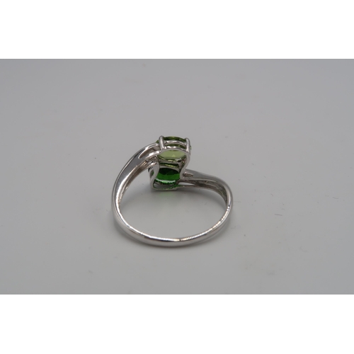 152 - A 9ct white gold and green stone crossover ring, likely peridot and tsavorite, size U, 3.9g.