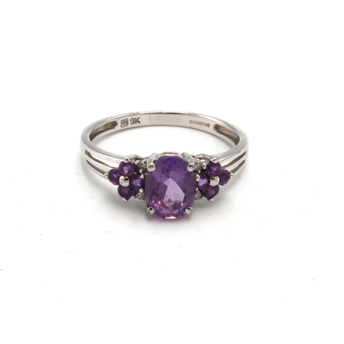 153 - A 9ct white gold, diamond and lilac stone dress ring, the central oval cut pale amethyst coloured st... 