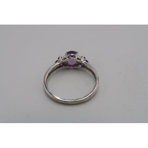 153 - A 9ct white gold, diamond and lilac stone dress ring, the central oval cut pale amethyst coloured st... 