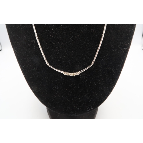 177 - A 9ct white gold and diamond necklace, the curved integral setting set with five small diamonds, len... 