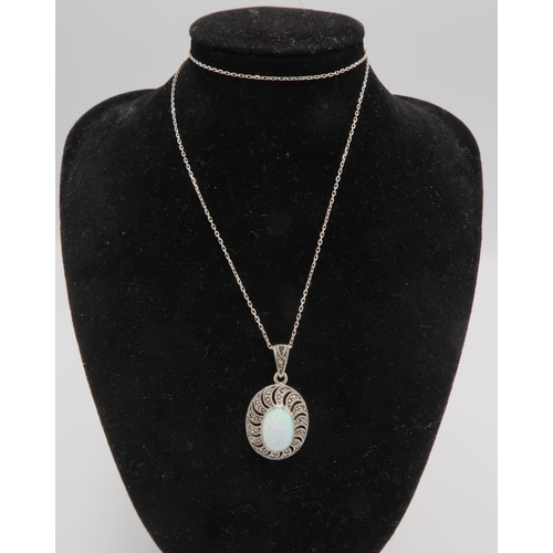 236 - An opal pendant, the oval opal of approximately 12 by 8mm in open backed silver setting with marcasi... 