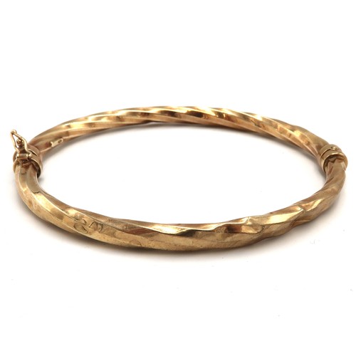 126 - A 9ct gold bangle, with twist detail, hinged and with safety clasp, internal diameter 5.8 by 6.5cm, ... 