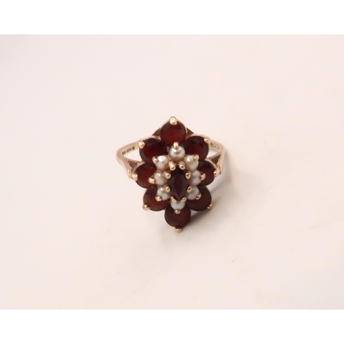120 - A 9ct gold, garnet and seed pearl dress ring of double flowerhead form, with central marquise cut ga... 