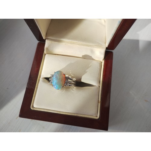 93 - An 18ct white gold, diamond and opal dress ring, the opal from Coober Pedy, Australia, with good mov... 