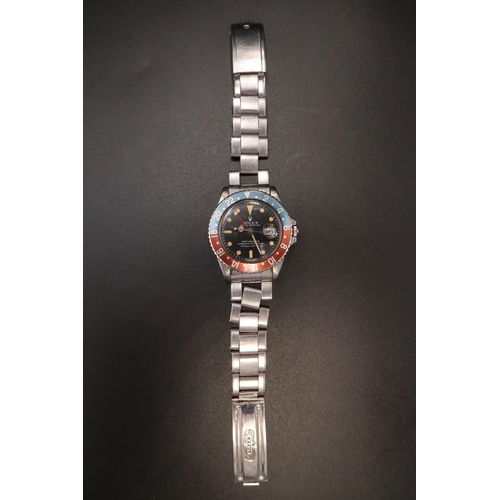 A Gents 1970's Rolex Oyster Perpetual GMT-Master, 'Pepsi', Reference 1675, 40mm. Featuring a Rolex signed black dial with luminous hour markers, date aperture, 'Mercedes' hands, centre seconds and arrow tipped dual time zone hand, the outer rotating blue and red 'Pepsi' bezel with Arabic numerals. No box or papers

Condition: The watch winds and ticks, but appears to be running fast. The acrylic crystal exhibits visible scoring. The dial shows an orange patina, consistent with age. The original riveted bracelet has three damaged links and a break at the clasp blade. Entered into auction by the original owner.