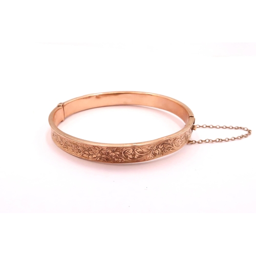 26 - A Rose Gold 9ct Hollow Bangle, with scroll work design to outer facing edge, with safety chain. 

We... 