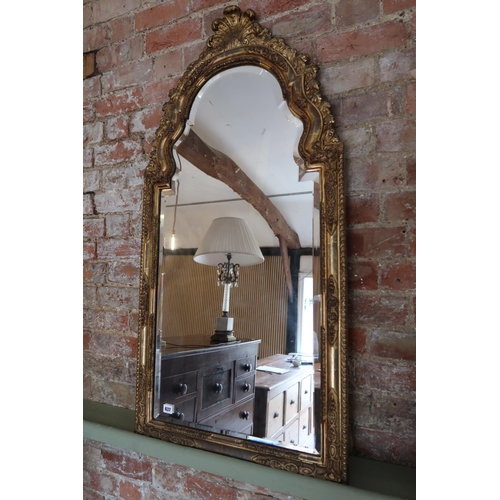 637 - A gilt mirror with an arched top and bevelled edged glass - Height 126cm x Width 62cm