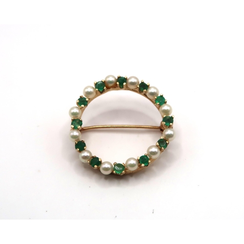 61 - A cultured pearl and emerald openwork circle brooch. Diameter 25mm. Tests gold 18ct. Weight 4.21 gra... 