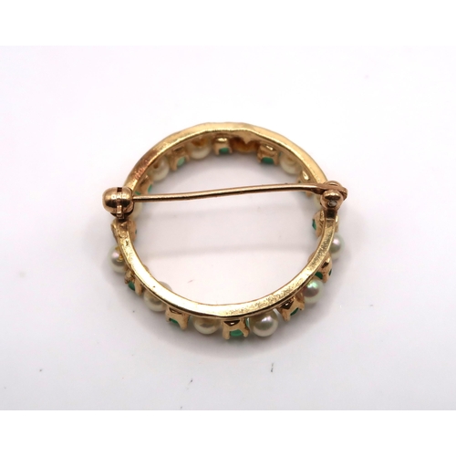 61 - A cultured pearl and emerald openwork circle brooch. Diameter 25mm. Tests gold 18ct. Weight 4.21 gra... 