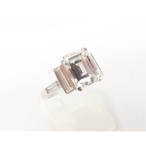 19 - A Deco Style Diamond Dress Ring - The central emerald cut diamond with a vertical baguette to each s... 