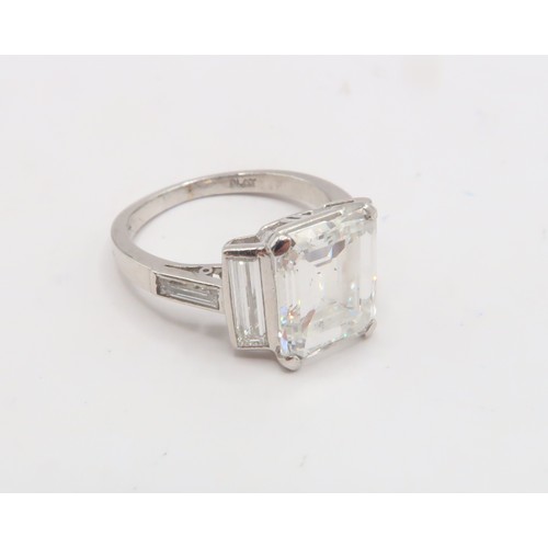 19 - A Deco Style Diamond Dress Ring - The central emerald cut diamond with a vertical baguette to each s... 