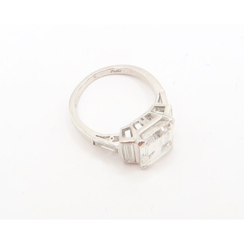 19 - A Deco Style Diamond Dress Ring - The central emerald cut diamond with a vertical baguette to each s... 