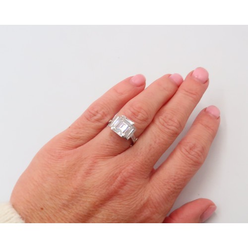 19 - A Deco Style Diamond Dress Ring - The central emerald cut diamond with a vertical baguette to each s... 