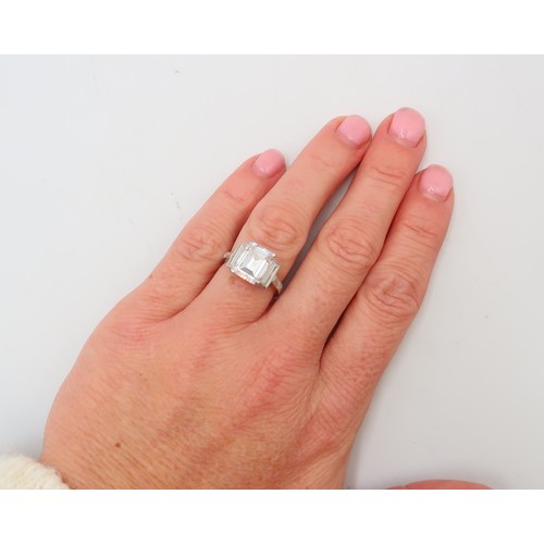 19 - A Deco Style Diamond Dress Ring - The central emerald cut diamond with a vertical baguette to each s... 