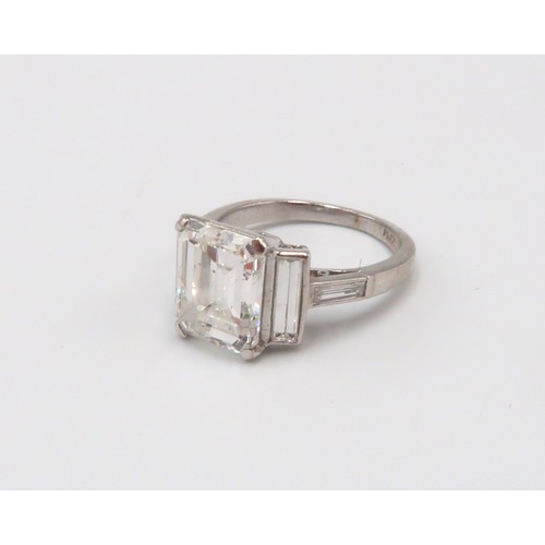 19 - A Deco Style Diamond Dress Ring - The central emerald cut diamond with a vertical baguette to each s... 