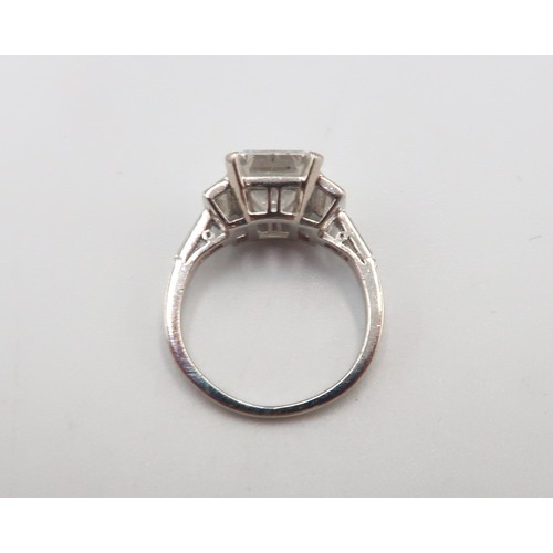 19 - A Deco Style Diamond Dress Ring - The central emerald cut diamond with a vertical baguette to each s... 