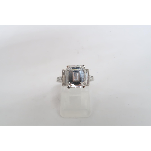 19 - A Deco Style Diamond Dress Ring - The central emerald cut diamond with a vertical baguette to each s... 