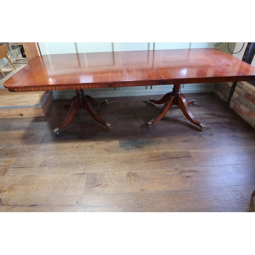 565 - An extending twin pedestal mahogany dining table with one leaf on twin quatrefoil supports, 77cm tal... 