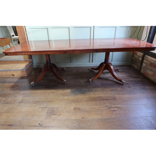 565 - An extending twin pedestal mahogany dining table with one leaf on twin quatrefoil supports, 77cm tal... 