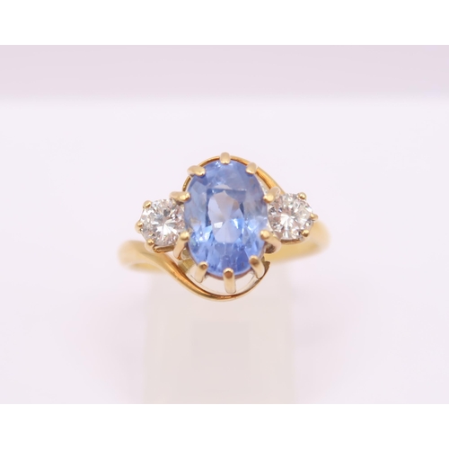  An 18ct gold oval sapphire and brilliant cut diamond crossover three stone ring. Estimated weight of... 
