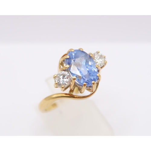  An 18ct gold oval sapphire and brilliant cut diamond crossover three stone ring. Estimated weight of... 