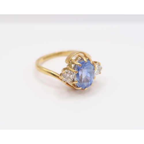  An 18ct gold oval sapphire and brilliant cut diamond crossover three stone ring. Estimated weight of... 