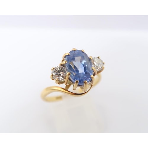  An 18ct gold oval sapphire and brilliant cut diamond crossover three stone ring. Estimated weight of... 