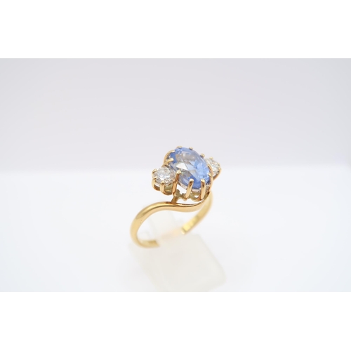  An 18ct gold oval sapphire and brilliant cut diamond crossover three stone ring. Estimated weight of... 