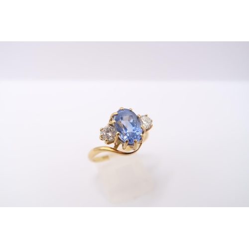  An 18ct gold oval sapphire and brilliant cut diamond crossover three stone ring. Estimated weight of... 