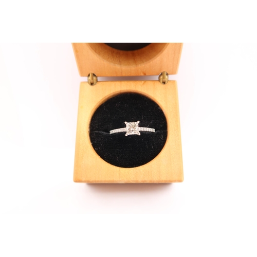  A princess cut diamond ring with brilliant cut diamonds to each shoulder. Estimated total diamond we... 