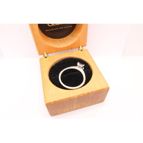  A princess cut diamond ring with brilliant cut diamonds to each shoulder. Estimated total diamond we... 